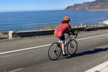 a person riding a bicycle next to the ocean