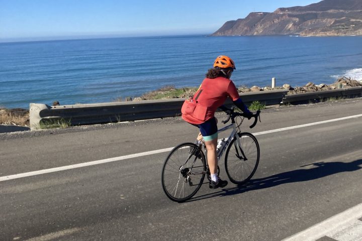 a person riding a bicycle next to the ocean